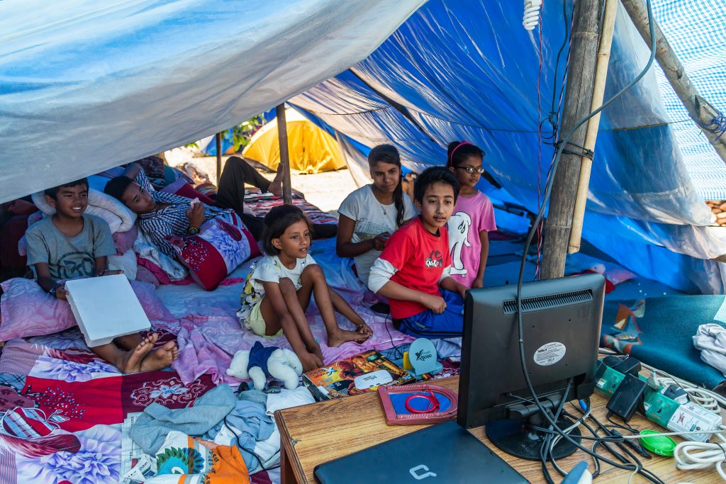children watching tv under a blue tent